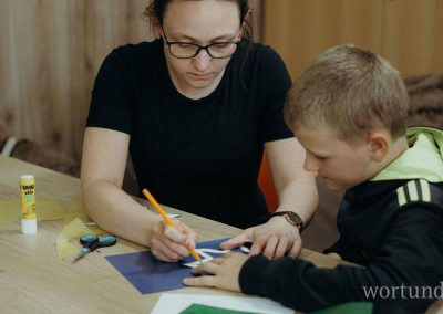 Young woman shows child how to cut out a star