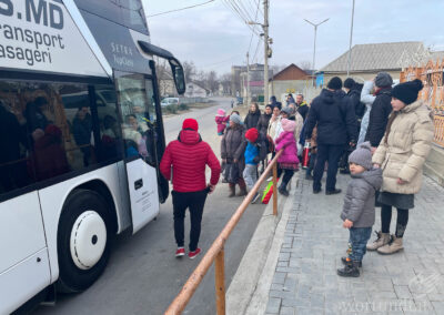 Frauen und Kinder stehen wartend vor einem Reisebus