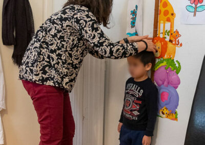 Kind an Messlatte - Frau misst die Größe des Kindes - Flüchtlinge in Griechenland