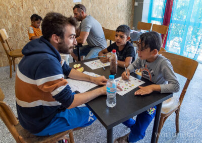 ein Helfer betreut zwei Schüler beim Lernen