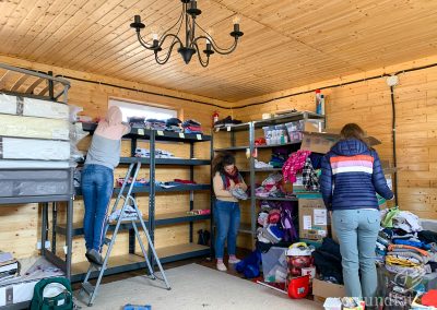 A room with shelves. Three woman sorting clothes