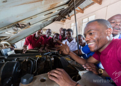 KFZ-Mechaniker stehen um eine geöffnete Motorhaube