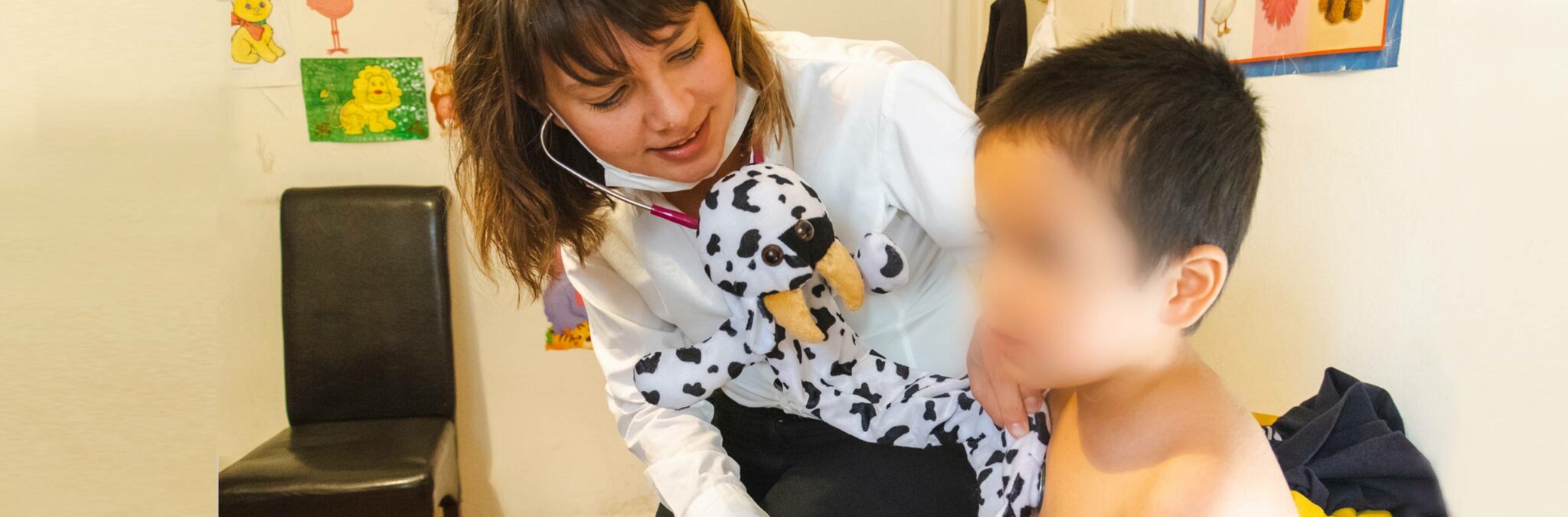 Kinderarzt-fuer-Fluechtlinge-in-Griechenland_wortundtat_slider_img Junge Ärztin hört kleinen Jungen ab