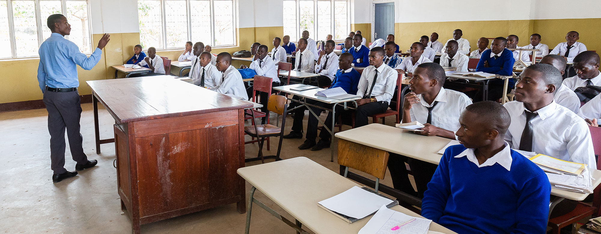 Lehrer-vor-Schulklasse-mit-jungen-Maennern_wortundtat_Tansania_KIUMA_Bildung Lehrer vor Schulklasse mit jungen Männern