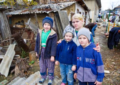Mother with her three children in front of her dilapidated house
