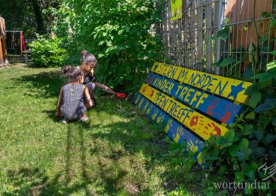 Two children on a meadow - a sign with the inscription Stern im Norden Kindertreff Teentreff - helping children in Germany