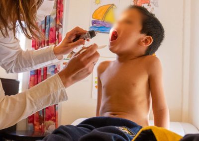 Child with mouth wide open - Doctor with lamp and spatula looks down throat - Refugees in Greece