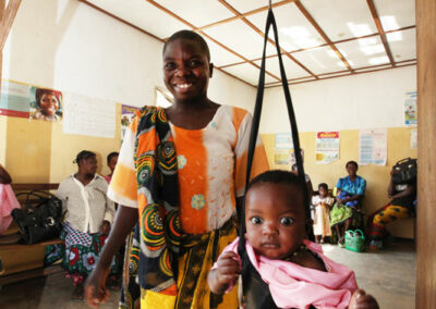 Säugling hängt in einer Körperwaage - die Mutter strahlt