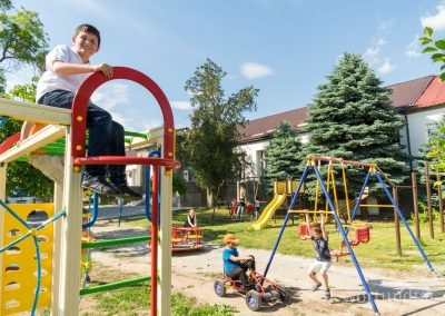 Boy on climbing frame in front of day care center