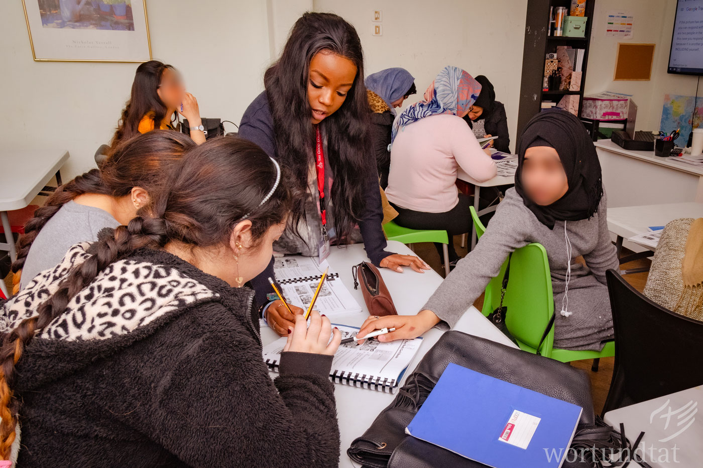 English courses provide young refugee women with a level of language skills, so they can understand and make themselves understood in the language. Teacher shows young women details of the English language