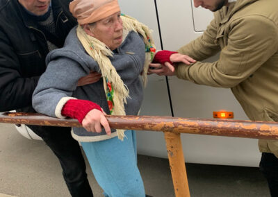 alte Frau wird von zwei Männern beim Gehen unterstützt