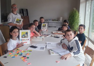 Children sitting around table showing their English learning books