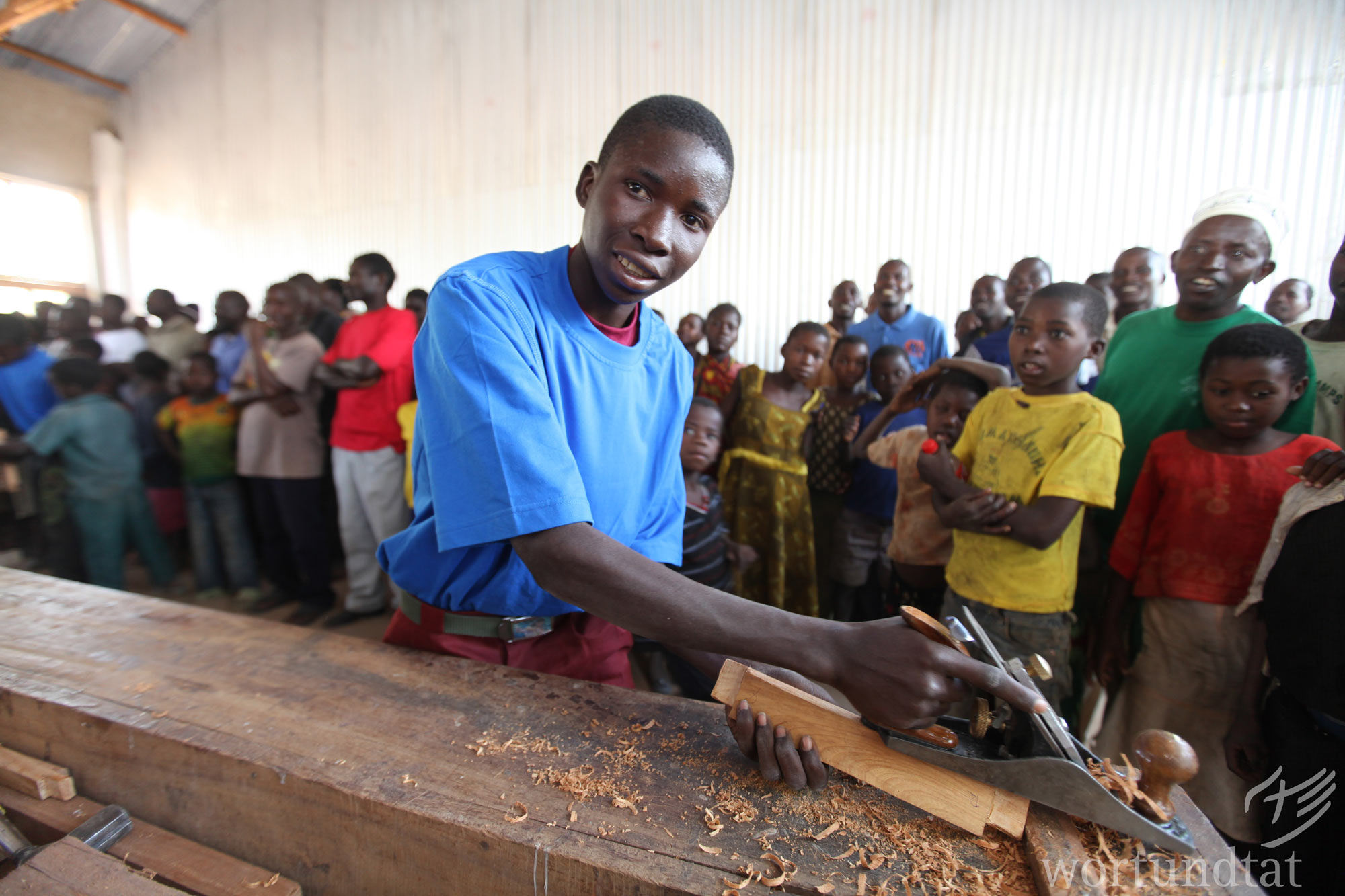 A young man shows what he has learned at the opening of a hope centre in southern Tanzania. A young man planes. Others watch.