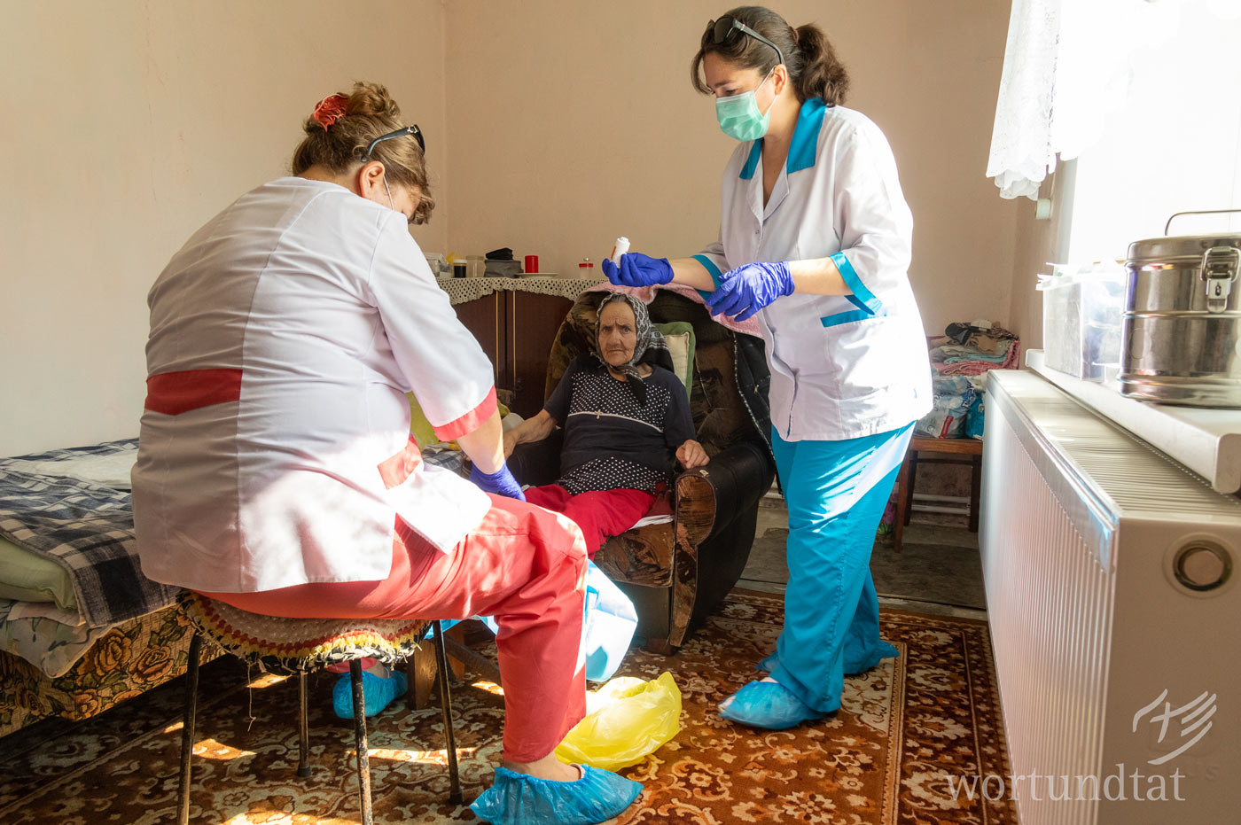If diabetes is not treated properly, circulation disorders may have permanent consequences for feet. 2 outpatient nurses treat the foot of a patient sitting in a chair
