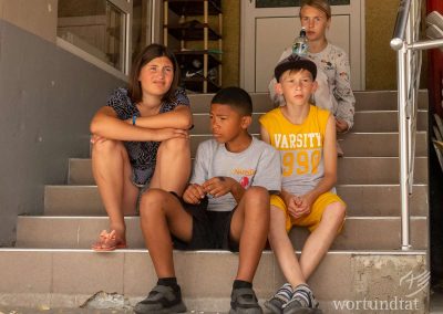 vier Kinder sitzen zusammen auf einer schattigen Treppe