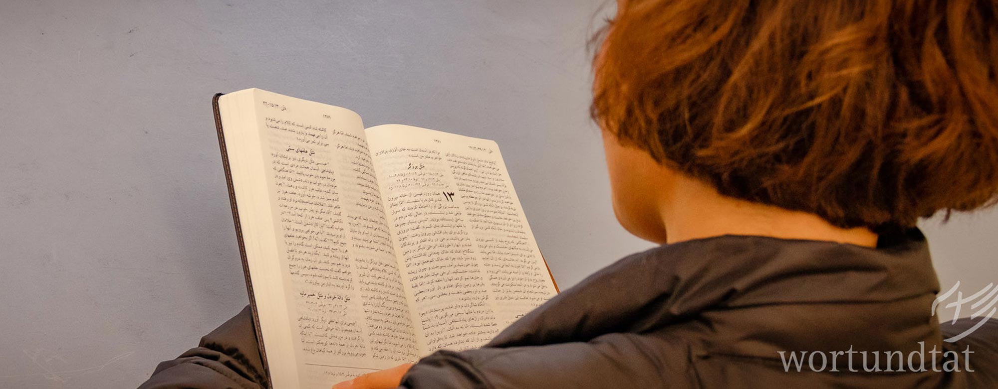 Frau liest in Bibel mit arabischen Schriftzeichen - Flüchtlinge in Griechenland