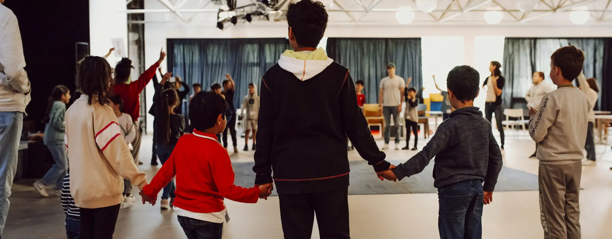 Kinderarmut Dortmund – Kinder stehen im Kreis und halten sich an den Händen beim Nachmittagsprogramm im Familienzentrum Stern im Norden 