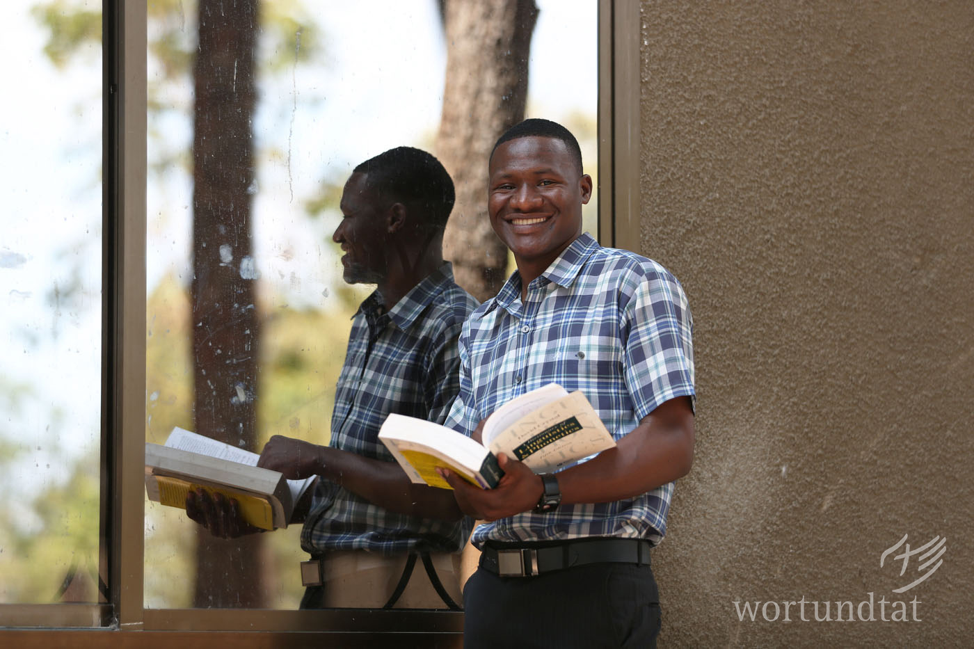 Athumani Rashid is happy to be able to teach children in Southern Tanzania. young man with book in front of a windowation_secondary-school