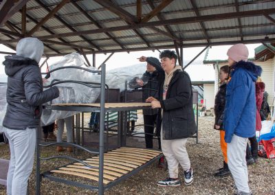 young people build beds for refugees housing